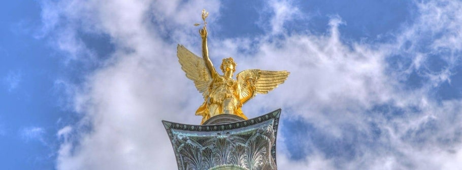 Goldene Engelstatue auf der Siegessäule vor blauem Himmel, bekanntes Wahrzeichen in München