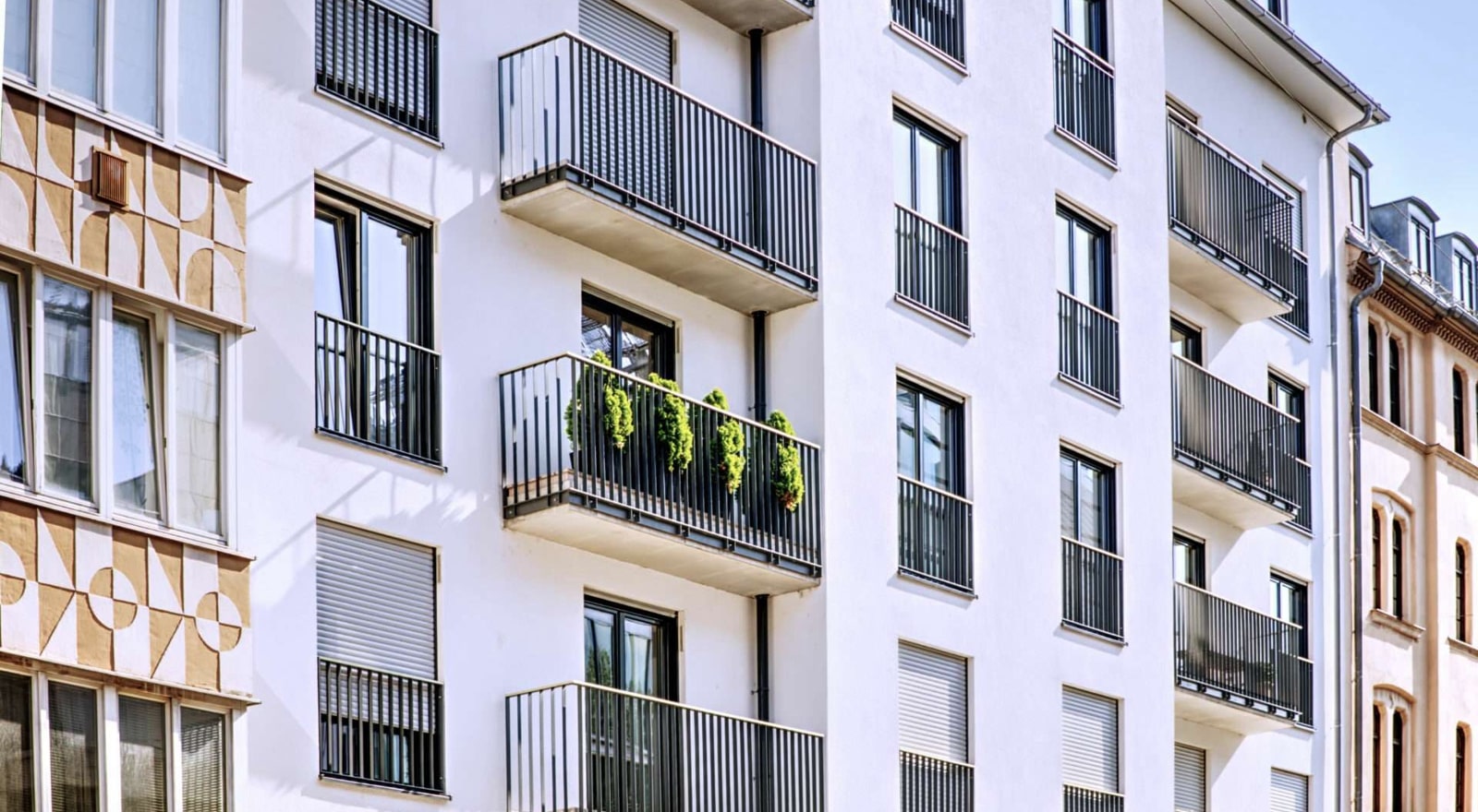 Fassade eines modernen Mehrfamilienhauses mit Balkonen und Bepflanzung in guter Wohnlage in München