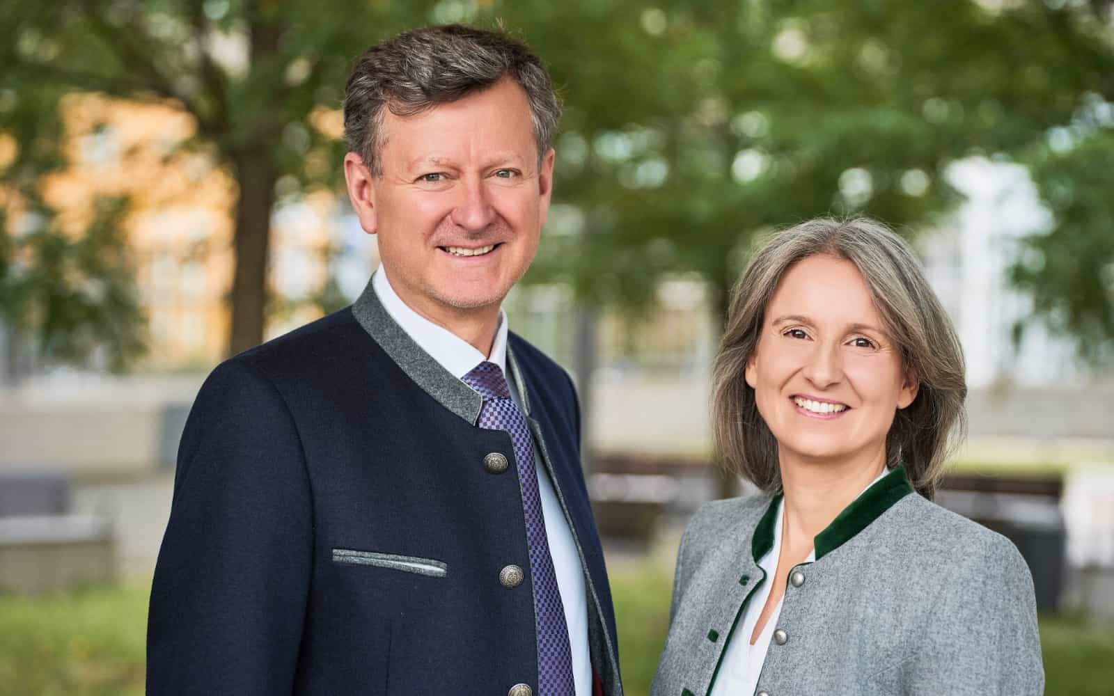Katerina und ihr Partner von Rogers Immobilien lächelnd im Freien vor Bäumen