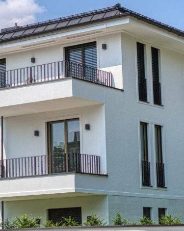 Detailaufnahme einer hellen Hausfassade mit übereinanderliegenden Balkonen und Metallgeländern in München
