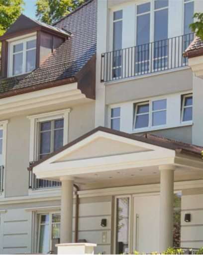 Detailaufnahme einer cremefarbenen Villa mit klassischem Säulenvordach und Dachgaube in München