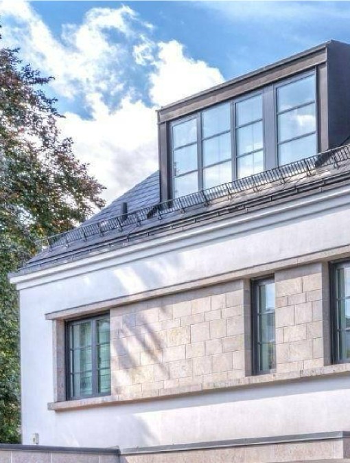 Detailaufnahme einer Dachgaube mit großen Fenstern an einer hellen Altbauvilla in München