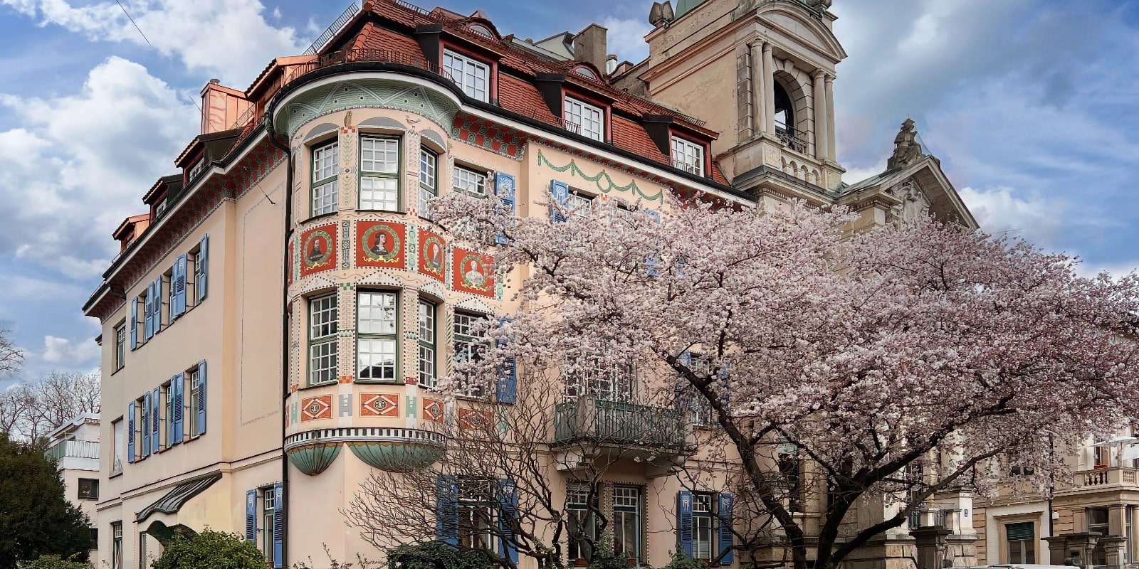 Historisches Jugendstilgebäude mit Turm und blühendem Kirschbaum in Schwabing