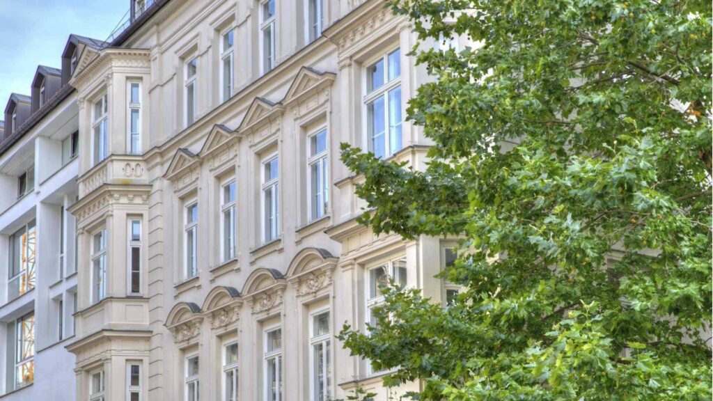 Historische Altbaufassade mit Erkern, teilweise verdeckt von einem Baum