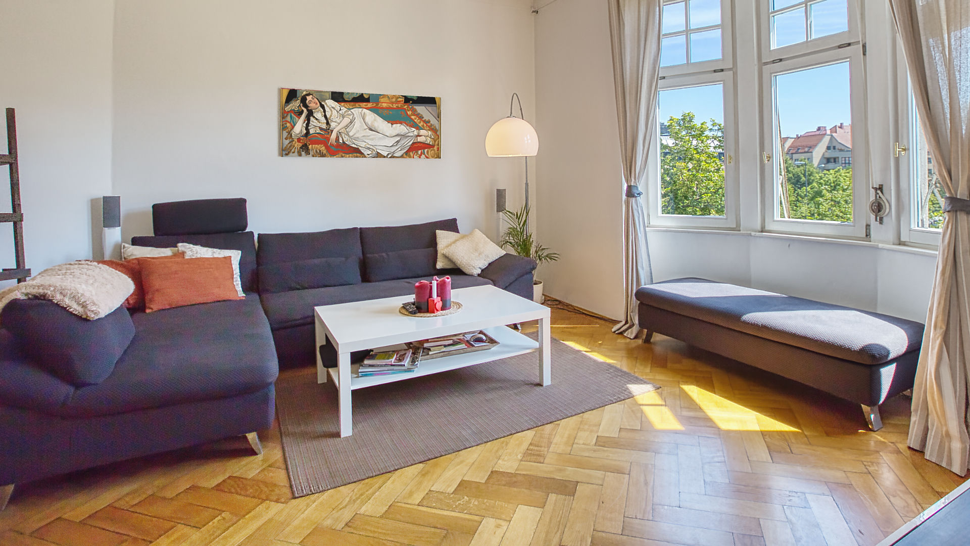 Wohnzimmer einer Altbauwohnung mit grauen Sofas und hohen Fenstern in München-Neuhausen