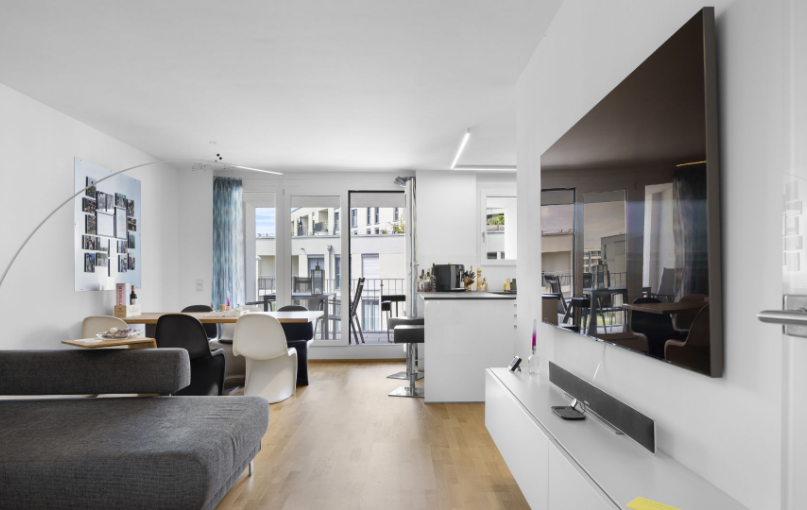 Offenes Wohnzimmer mit grauem Sofa und Blick zur Küche in einer Wohnung in München-Aubing