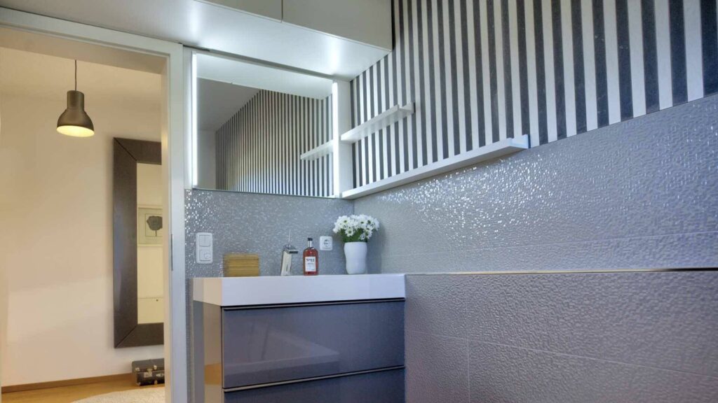 Modernes Badezimmer mit grauen Fliesen, großem Spiegel und cleanem Design