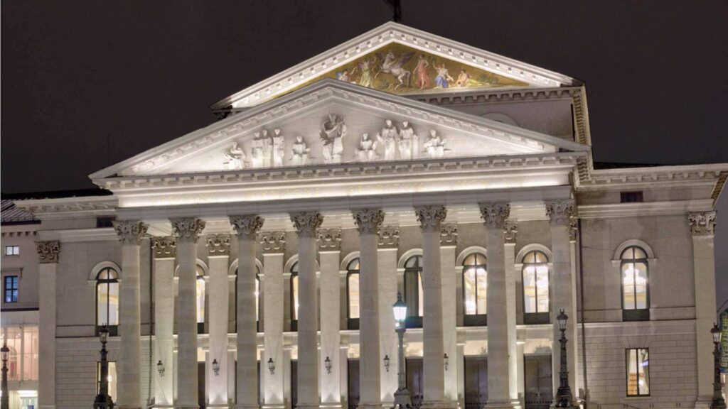 Beleuchtete Fassade der Bayerischen Staatsoper in München bei Nacht mit klassizistischen Säulen