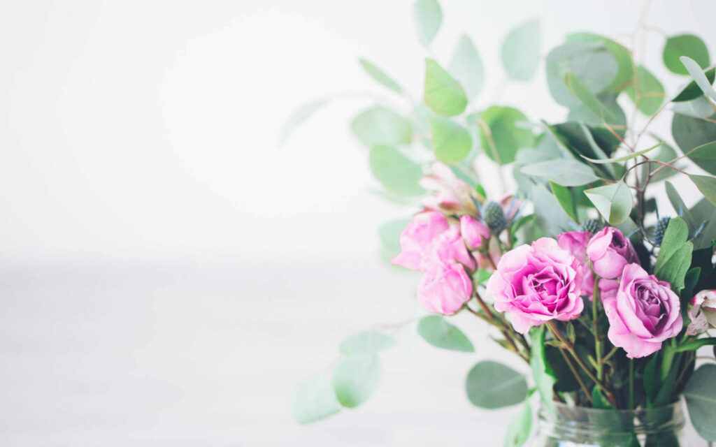 Blumenstrauß aus rosa Rosen und Eukalyptuszweigen in heller, minimalistischer Umgebung