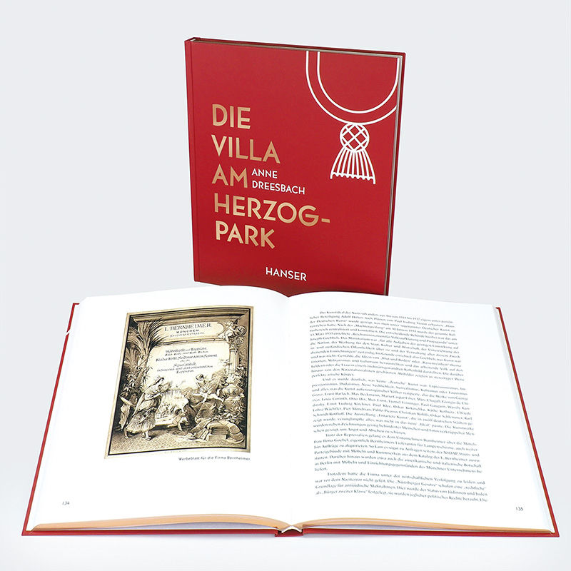 Aufgeschlagenes Buch 'Die Villa am Herzogpark' des Carl Hanser Verlags neben dem roten Buchcover