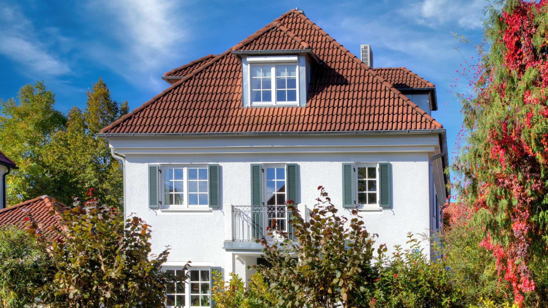 White detached house with a red roof and autumn leaves in the Munich district of Hadern