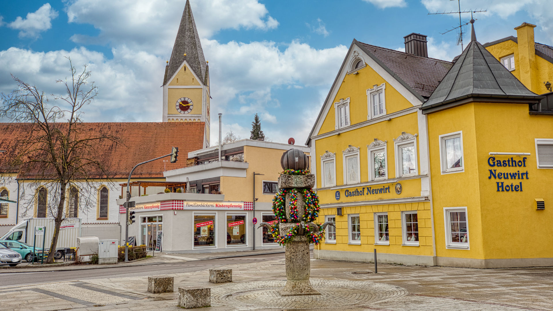 Historischer Marktplatz mit Kirchturm, Brunnen und gelben Fassaden im Ortskern von Garching bei München