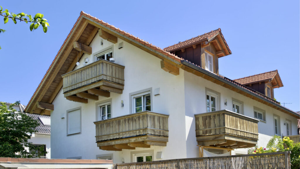 Bayerisches Wohnhaus mit hölzernen Balkonen unter blauem Himmel