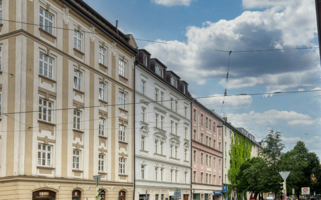 Reihe bunter Altbaufassaden entlang einer breiten Münchner Straße