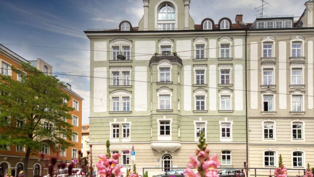 Historische Altbaufassade mit Erkern und blühenden Blumen im Vordergrund