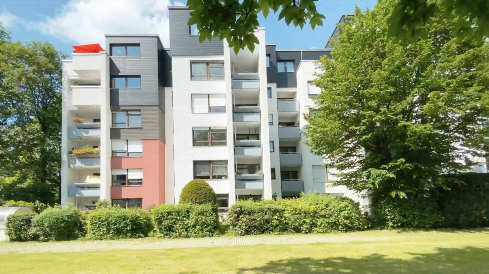 Modernes mehrstöckiges Wohnhochhaus mit Balkonen und Grünanlage im Sonnenschein