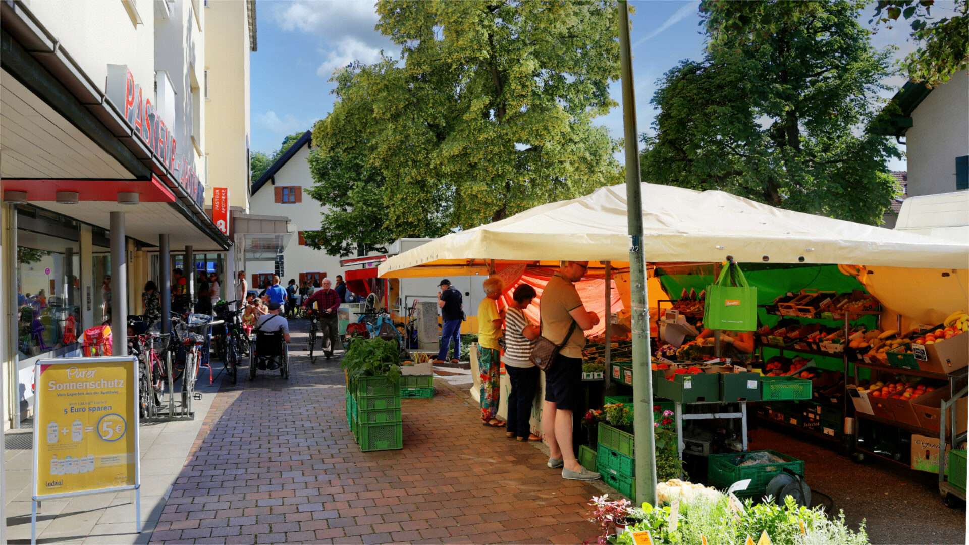 Busy weekly market with market stalls and parasols in the Munich district of Hadern