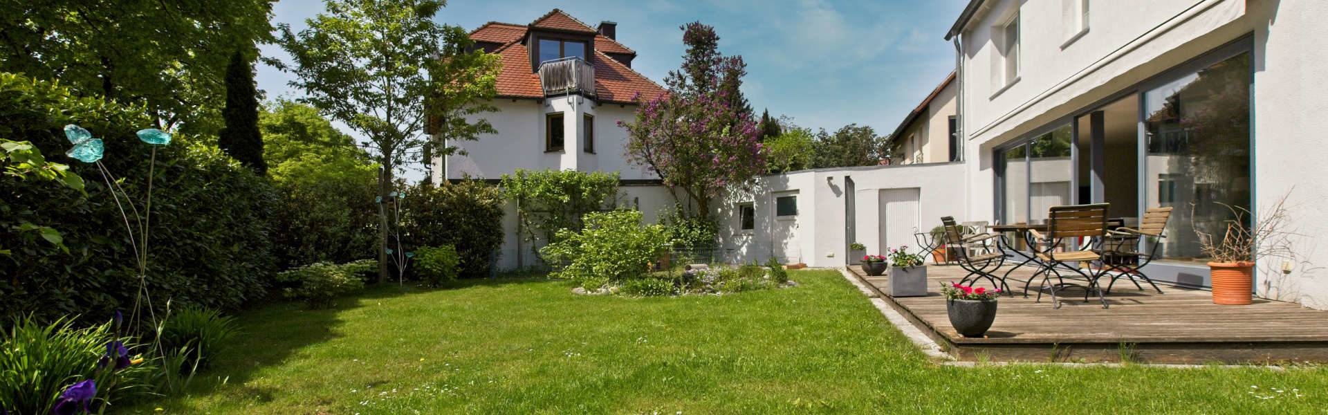 Weißes Haus mit Gartenterrasse und gemütlicher Sitzgruppe im Grünen in Planegg bei München