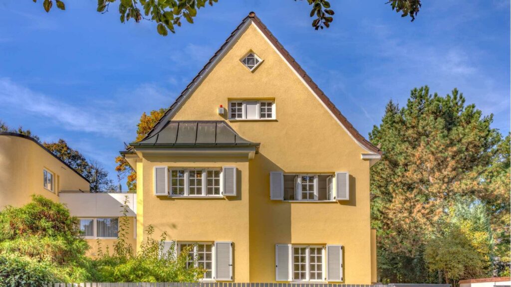 Historisches gelbes Wohnhaus mit Satteldach und grauen Fensterläden