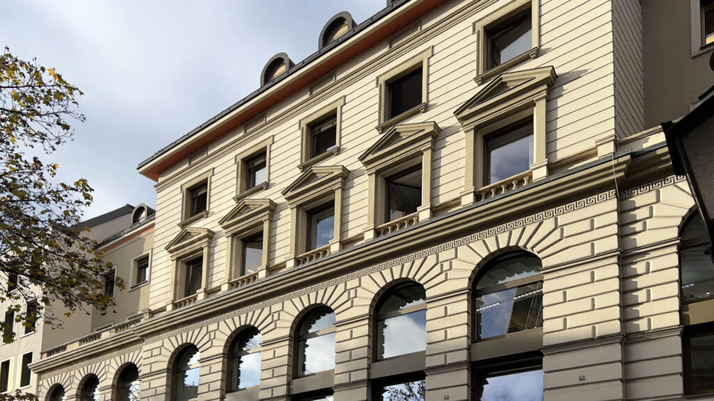 Historische Fassade eines Altbaus mit Bogenfenstern in schräger Straßenansicht