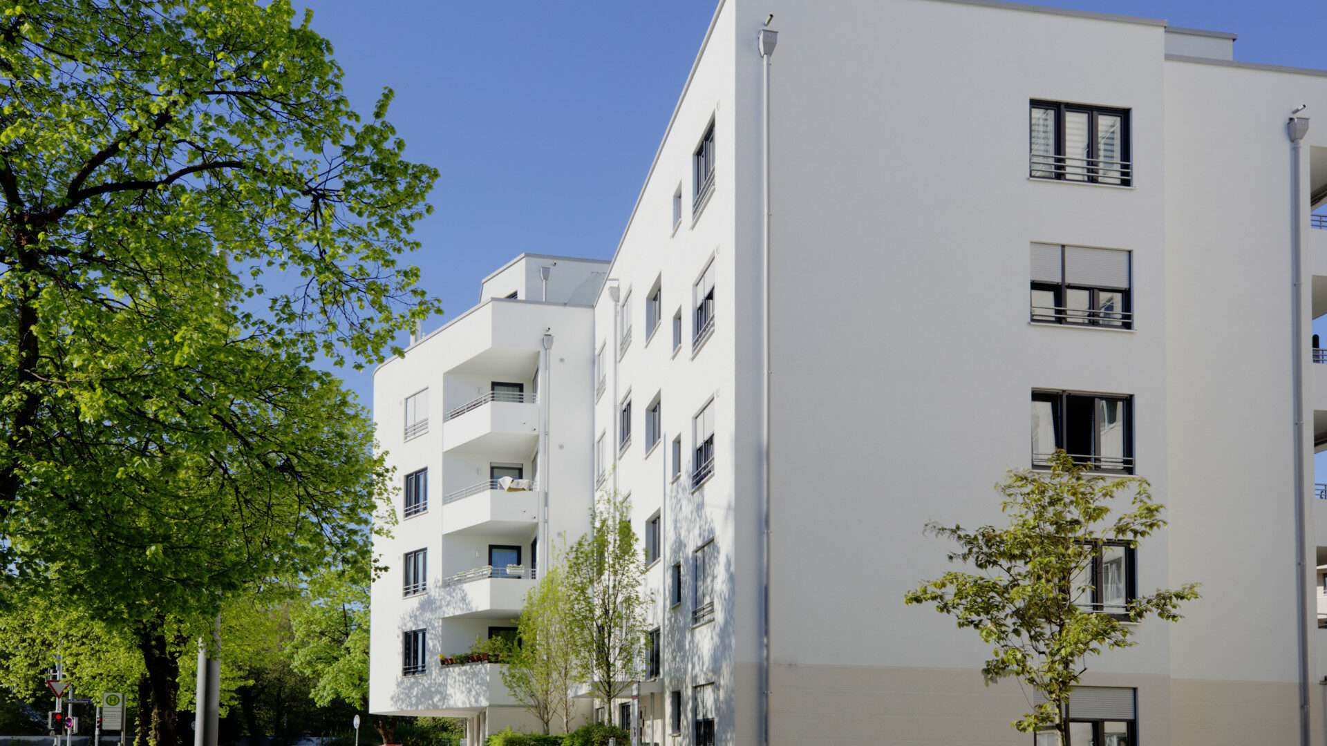 Modernes weißes Hochhaus mit runden Balkonen und Bäumen im Münchner Stadtteil Giesing