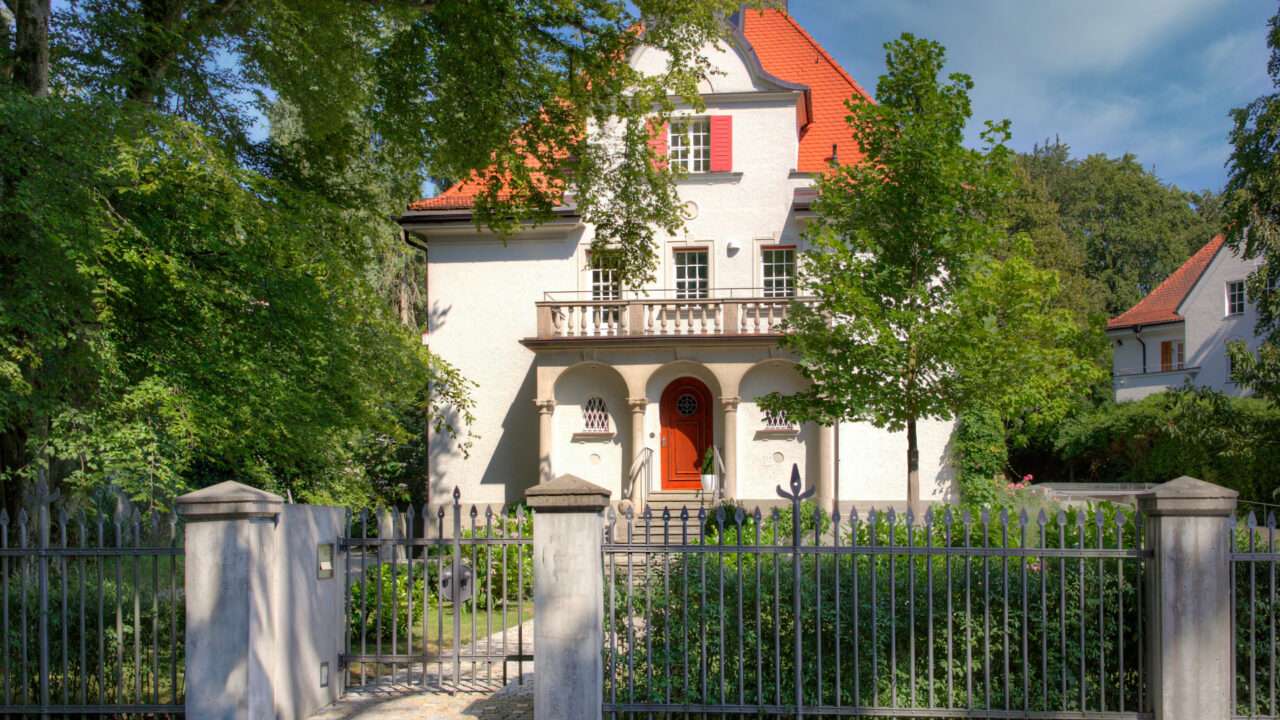 Repräsentative weiße Villa mit rotem Walmdach und gepflegtem Vorgarten im Münchner Stadtteil Solln