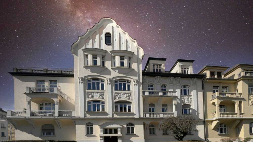 Historische Stadtvilla mit reich verzierter Fassade bei Nacht unter Sternenhimmel