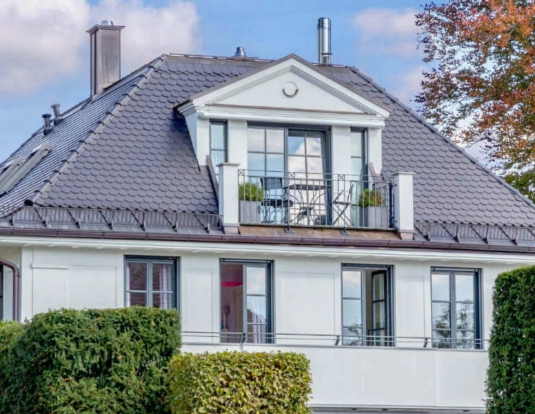 Weiße Villa mit Gaube und gepflegter Hecke im Vorgarten in München