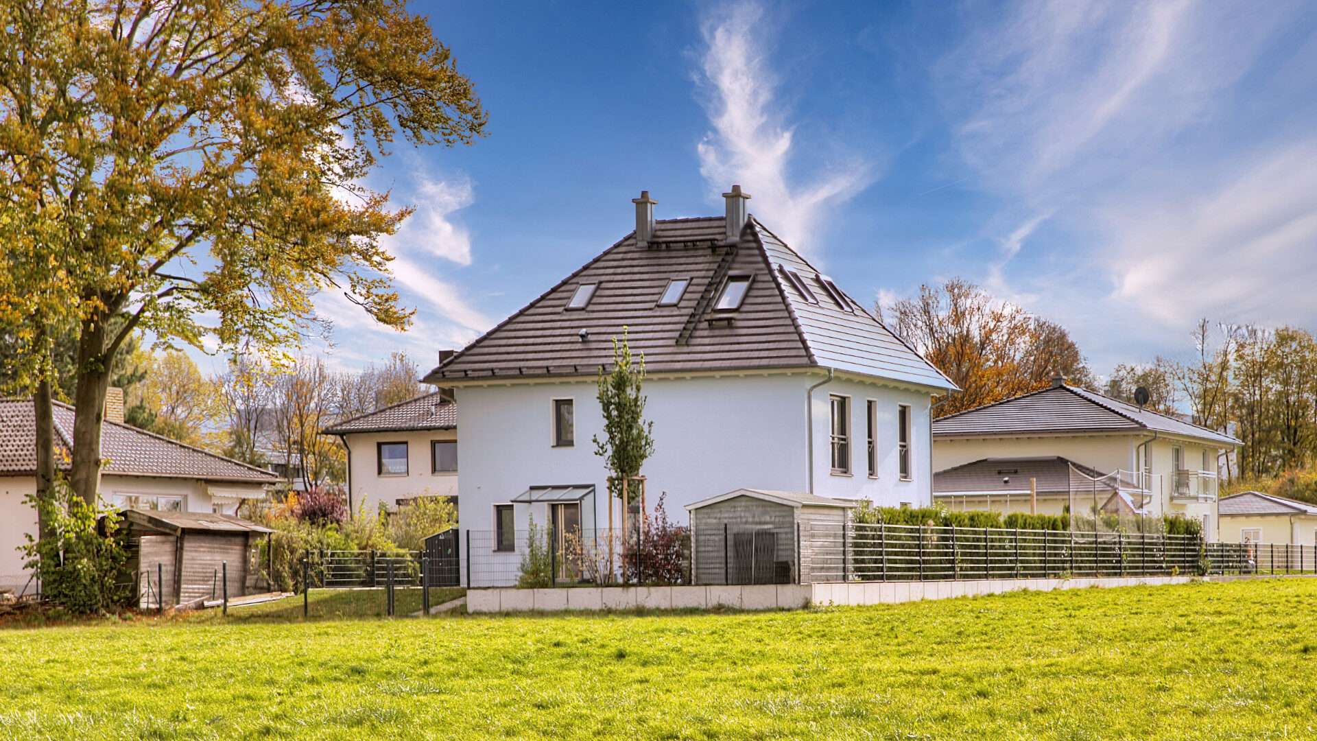 Weißes Einfamilienhaus mit dunklem Dach und großer Rasenfläche im Münchner Stadtteil Aubing