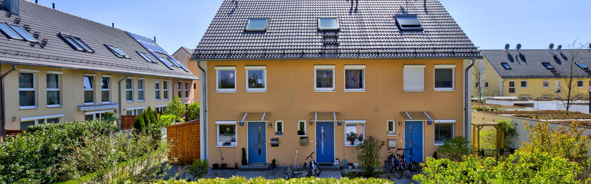 Orangefarbene Reihenhauszeile mit Solaranlage und blauen Türen im Münchner Stadtteil Feldmoching