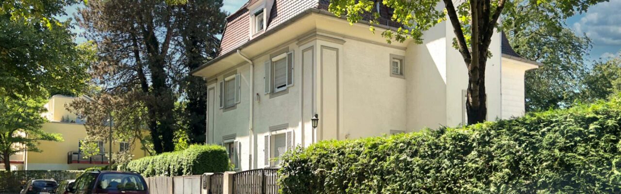Gepflegtes Wohnhaus hinter hoher Hecke mit altem Baumbestand in der Gemeinde Ismaning bei München