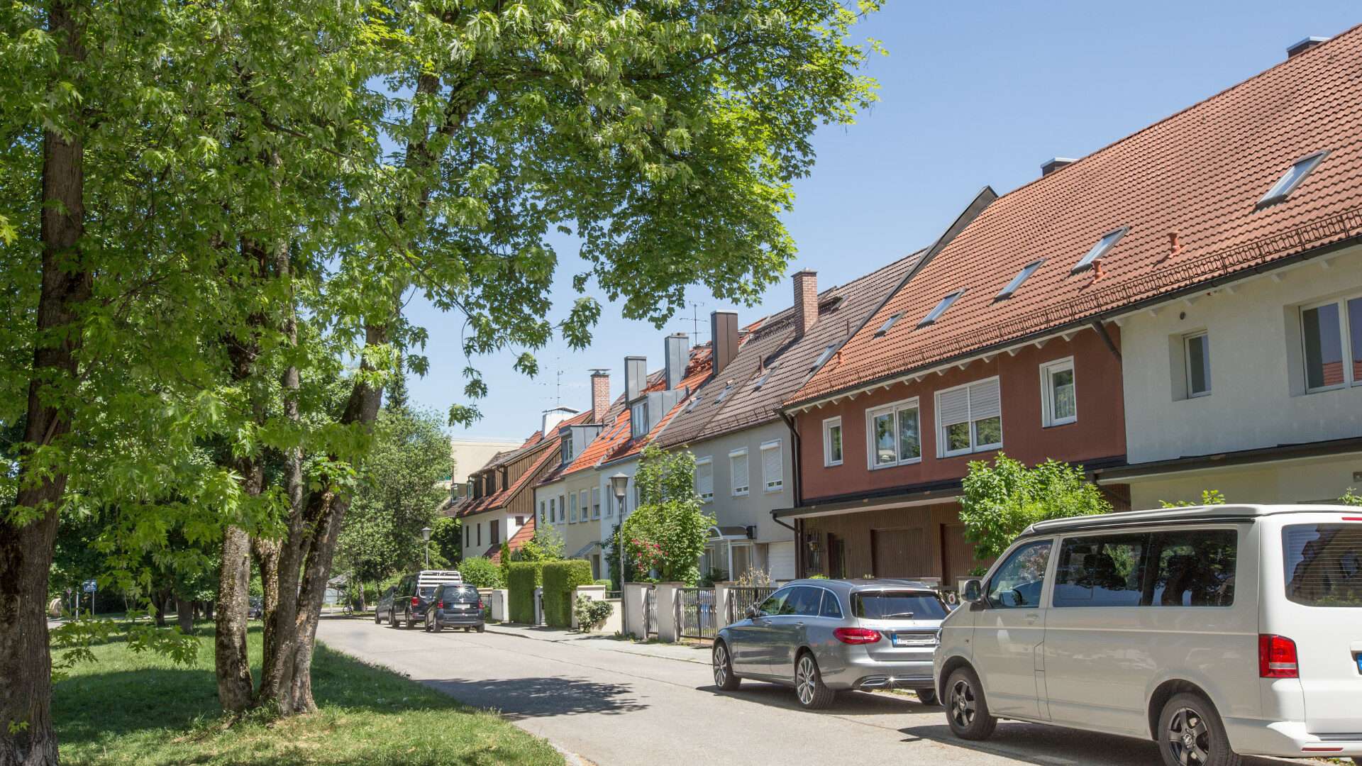 Rote Reihenhaus-Wohnsiedlung mit Bäumen und parkenden Autos im Münchner Stadtteil Laim