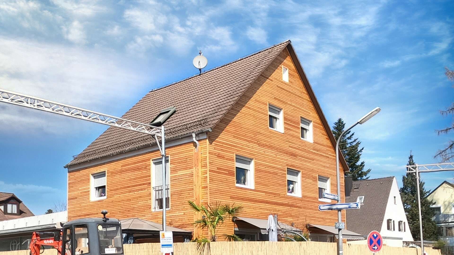 Haus mit Holzfassade im Rohbau und Baukran in der Gemeinde Neuried bei München