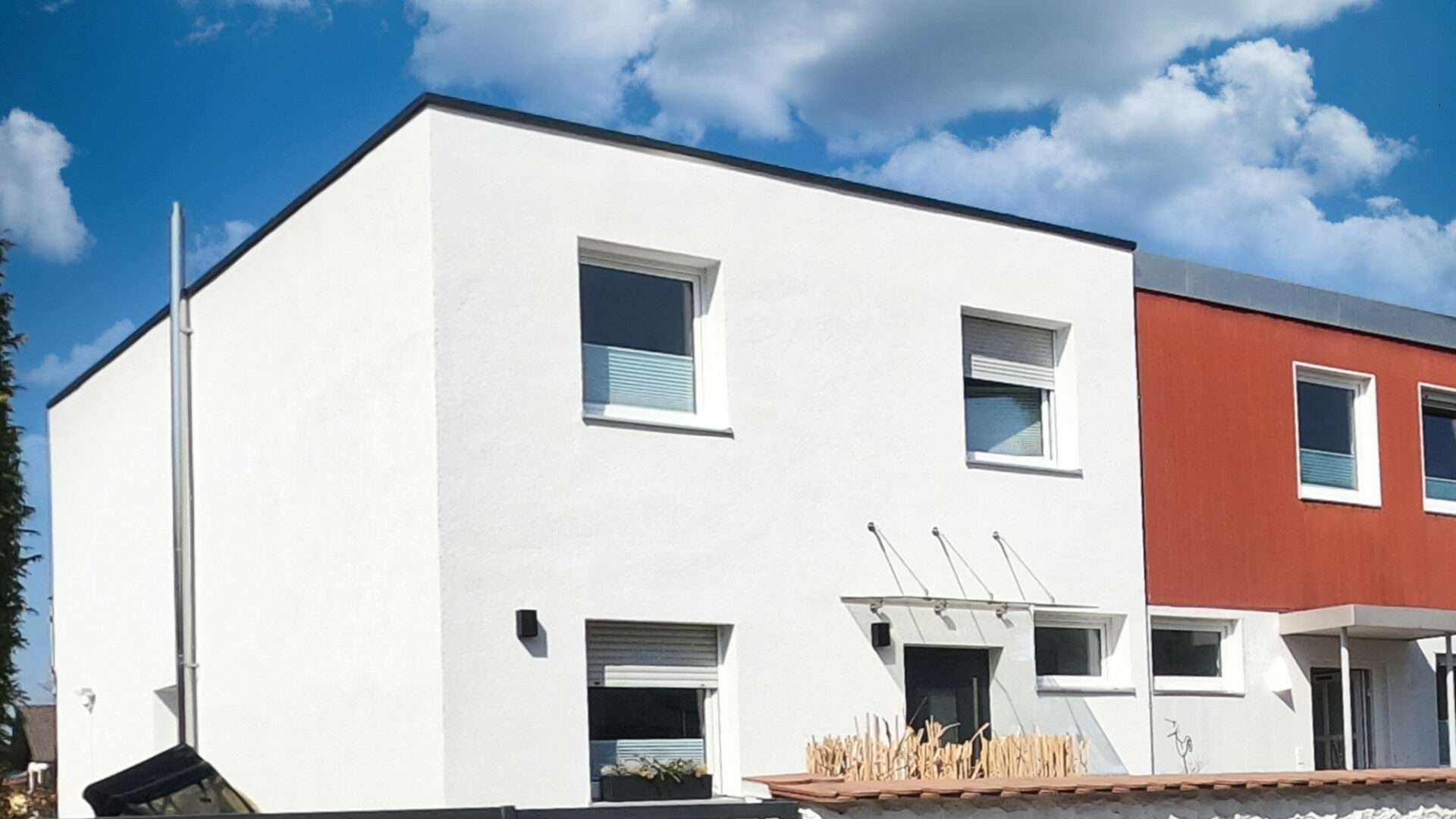 Weiße Doppelhaushälfte mit terrakottafarbener Nachbarhälfte in der Gemeinde Neuried bei München