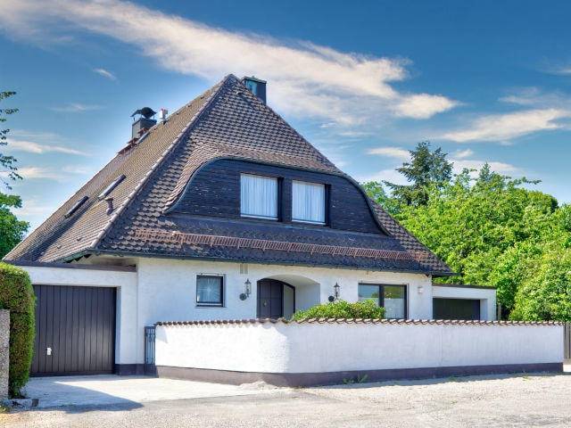 Einfamilienhaus mit steilem dunklem Dach und Garageneinfahrt in München-Obermenzing