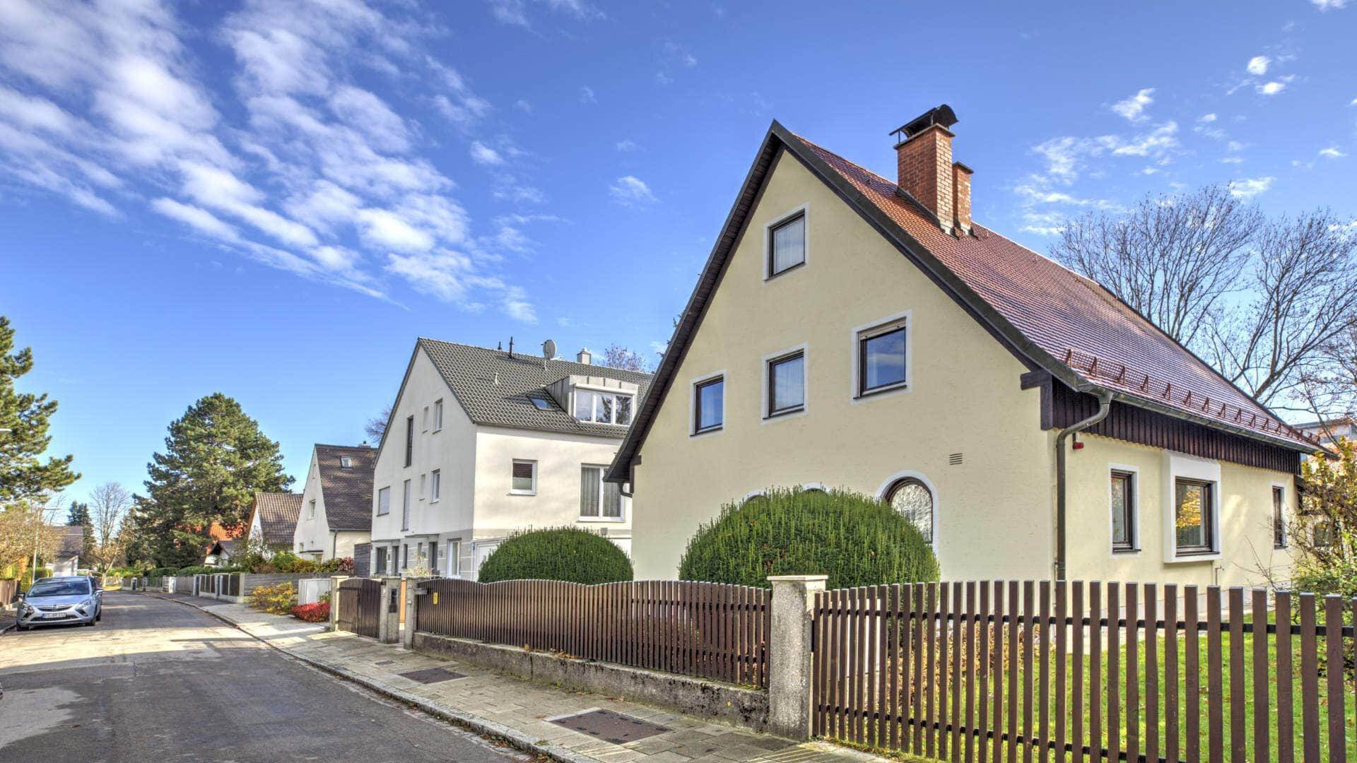Beiges Wohnhaus mit rotem Ziegeldach und Holzzaun im Münchner Stadtteil Sendling-Isarvorstadt