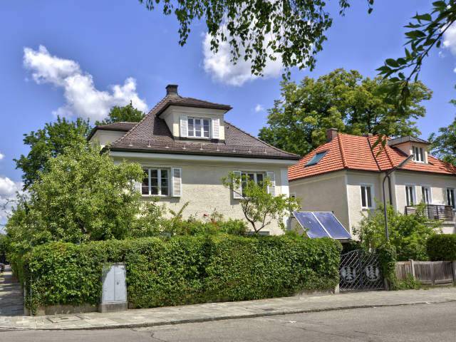Cremefarbenes Haus mit rotem Dach hinter grüner Hecke in München-Untermenzing