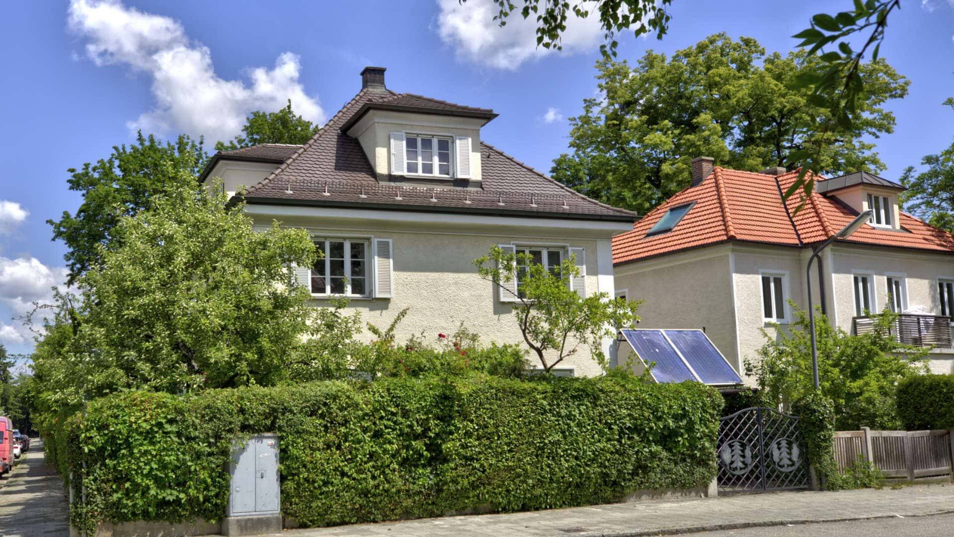Cremefarbenes Haus mit rotem Dach und dichter Hecke im Münchner Stadtteil Untermenzing