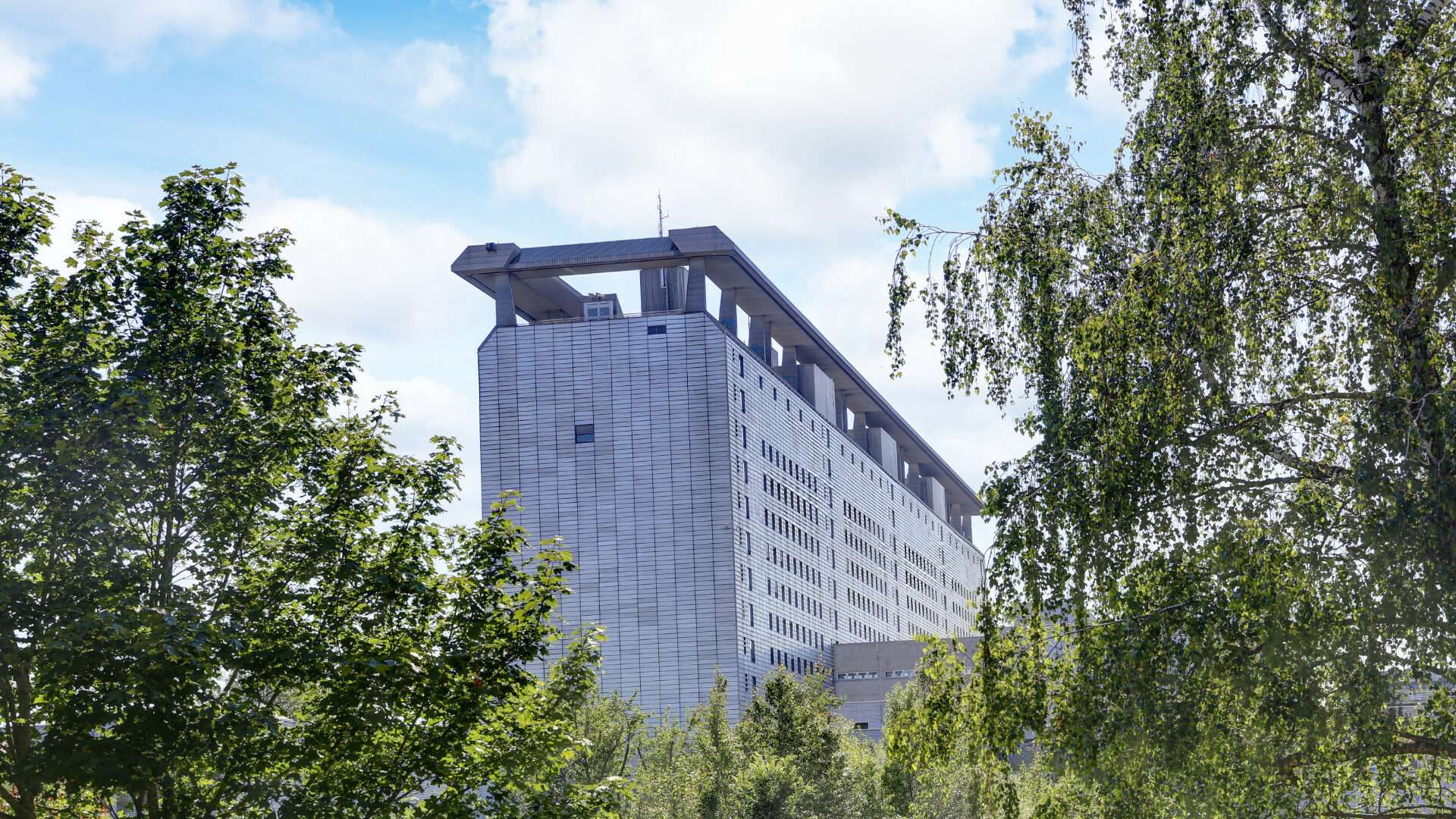 High-rise building of the Großhadern Clinic nestled in green trees in the Munich district of Hadern