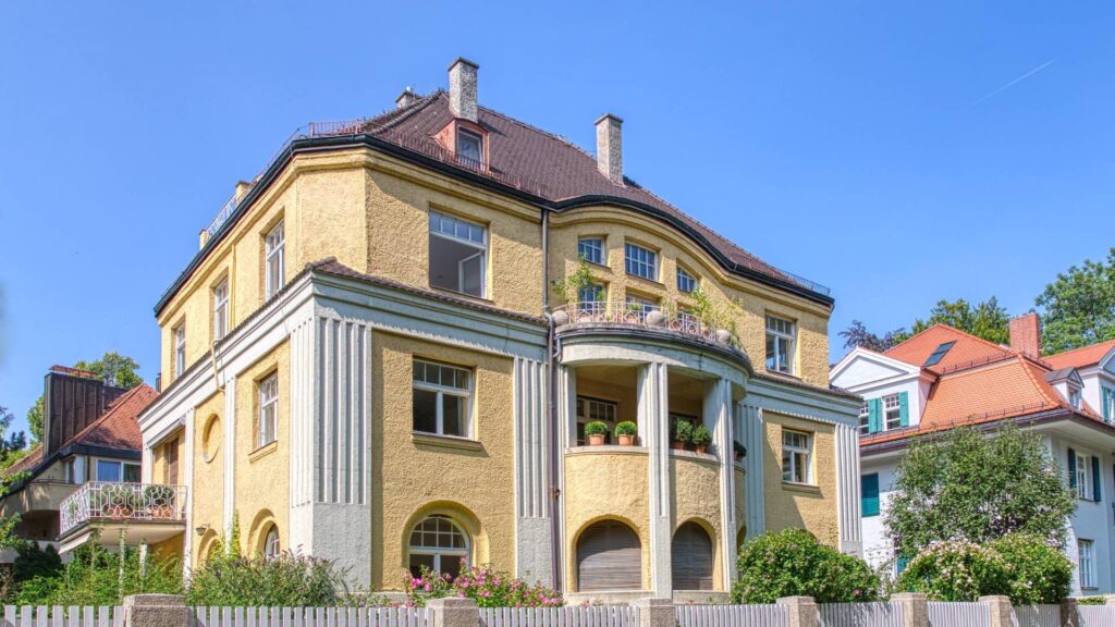 Historische gelbe Stadtvilla mit weißen Säulen und rundem Erker
