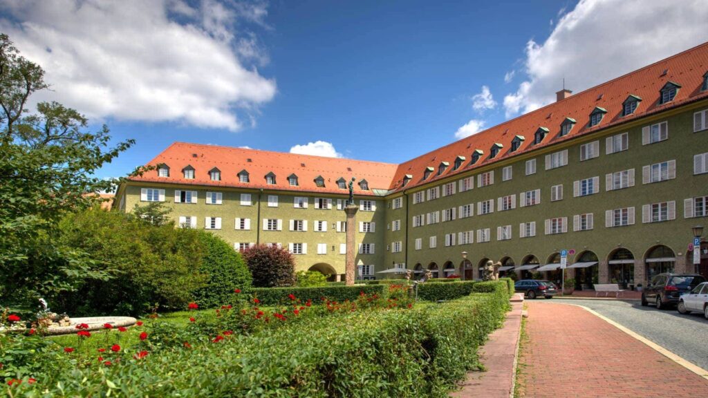 Historischer Wohnkomplex mit rotem Ziegeldach und gepflegter Grünanlage in München