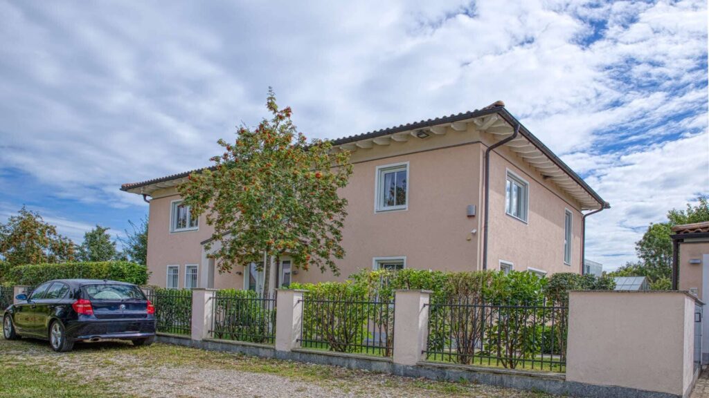 Lachsfarbenes zweistöckiges Wohnhaus mit Zaun und parkendem Auto