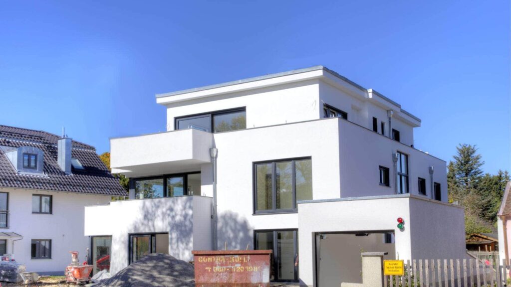 Modernes kubisches Einfamilienhaus mit weißer Fassade und großen Fensterflächen in München-Hadern