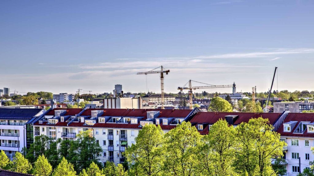 Blick über Wohnhäuser mit Baukran im Hintergrund in München-Lochhausen im Frühling