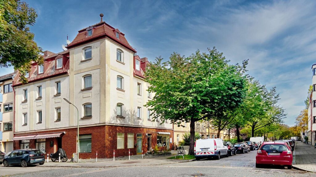 Historisches Eckgebäude mit rotem Dach an einer Münchner Straßenkreuzung