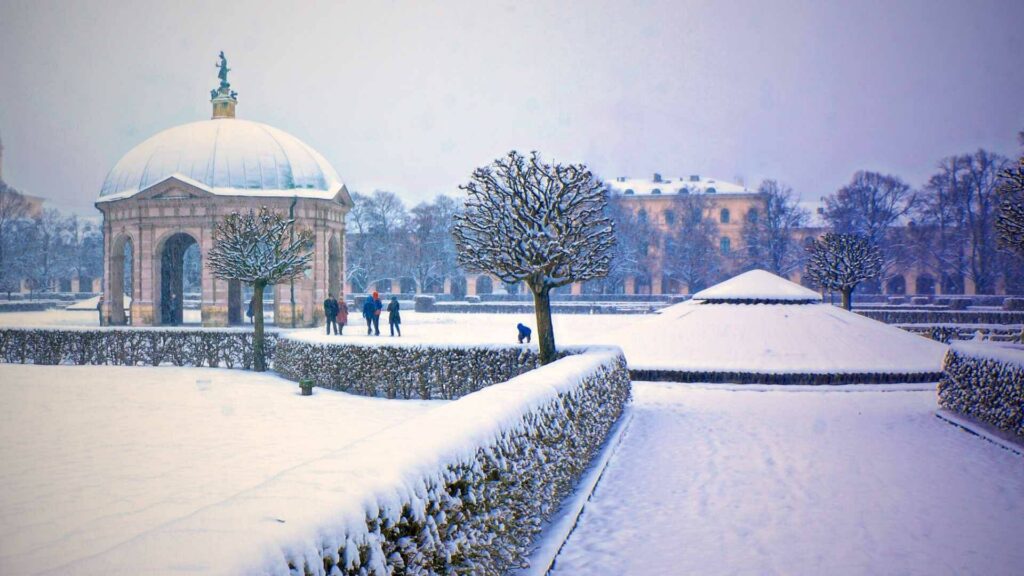 Verschneiter Park mit historischem Pavillon und Gebäude im Winter
