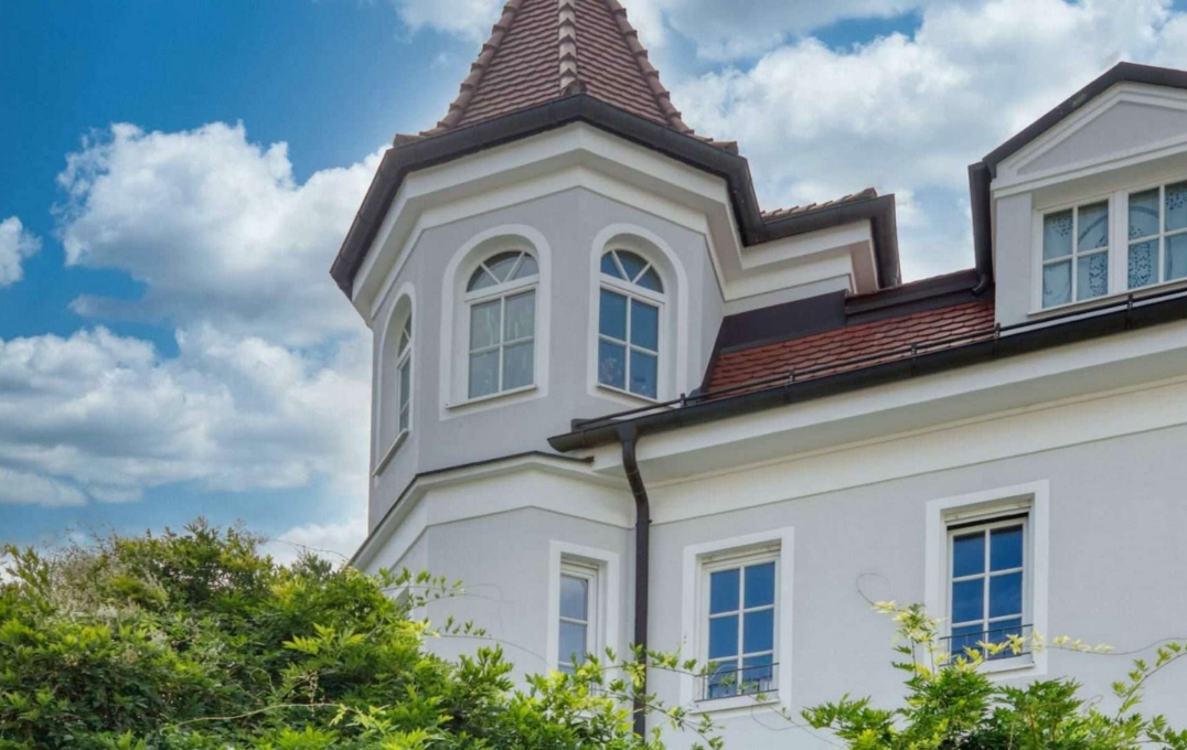 Weiße Villa mit Eckturm und rotem Ziegeldach im Münchner Stadtteil Nymphenburg