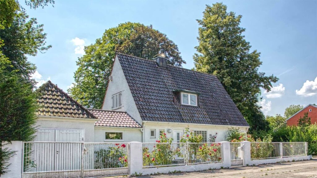 Weißes Einfamilienhaus mit steilem Satteldach und gepflegtem Vorgarten in München