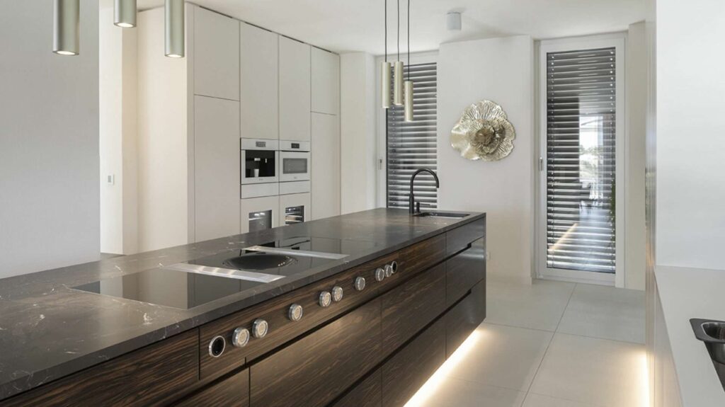 Moderne Designküche mit dunkler Kochinsel und eleganten Pendelleuchten in einer Villa in Regensburg