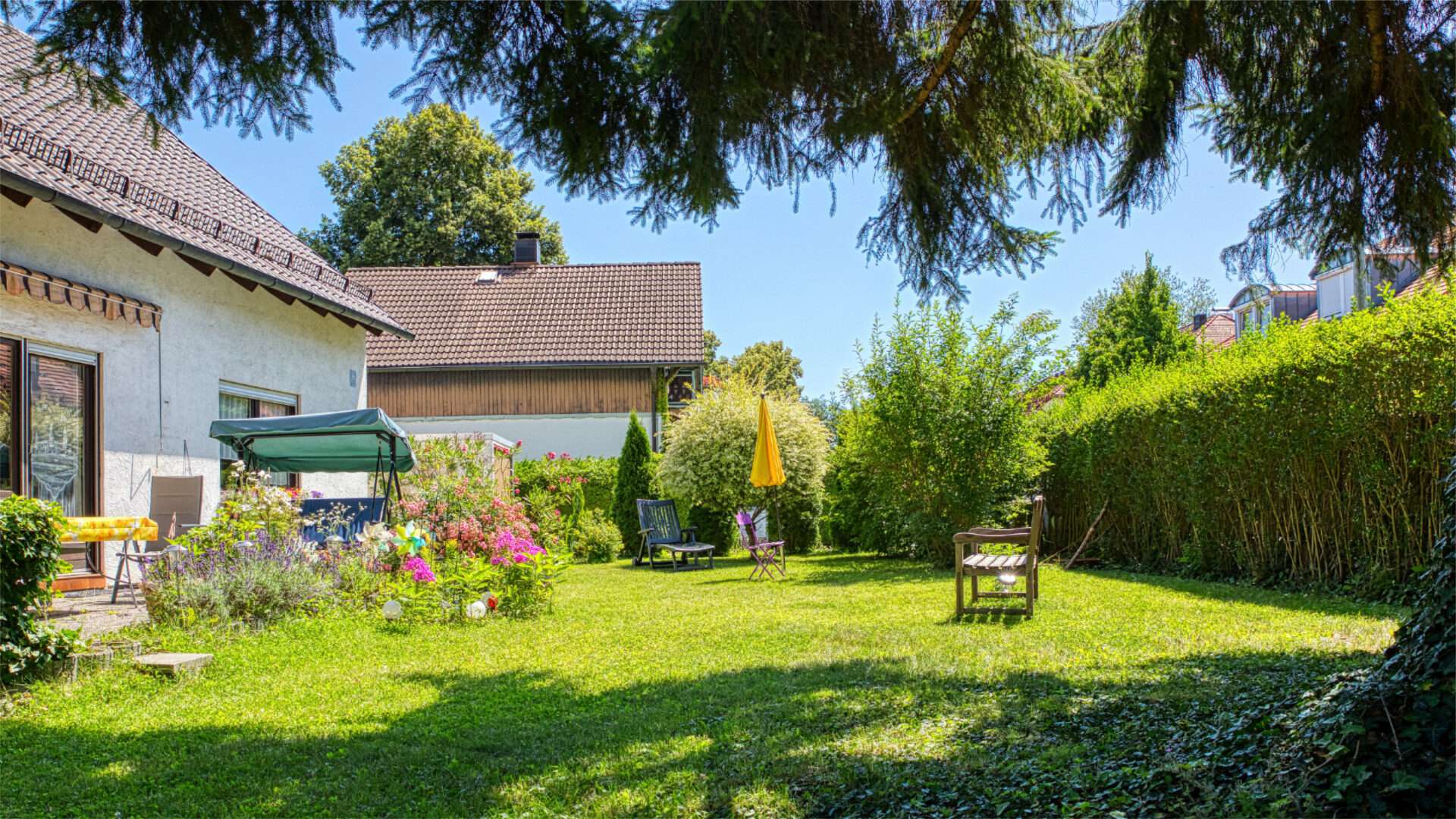 Gepflegter Garten mit Rasenfläche, Hecke und Sitzgelegenheit im Münchner Stadtteil Forstenried